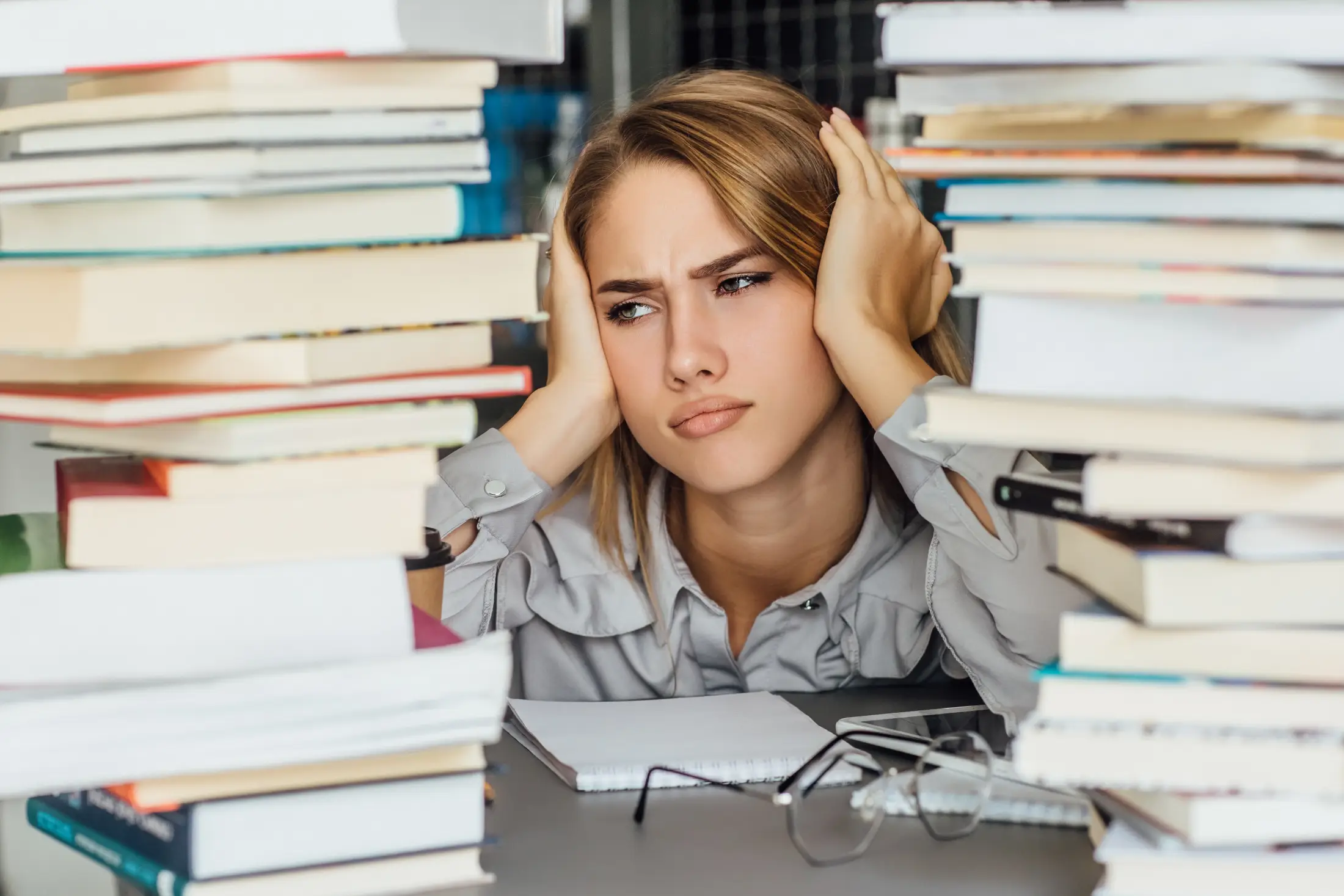 unhappy-young-college-student-woman-library-posing-with-glasses-books errores de estudios